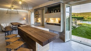Une cuisine moderne avec un îlot central en bois, des tabourets de bar et une vue sur un jardin luxuriant.