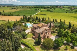 A villa with a swimming pool, surrounded by lush greenery and fields. - Casale Dei Girasoli 14 (Cortona)