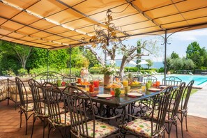 An outdoor dining area with a covered table, chairs, and a decorative centerpiece. - Casale Dei Girasoli 14 (Cortona)