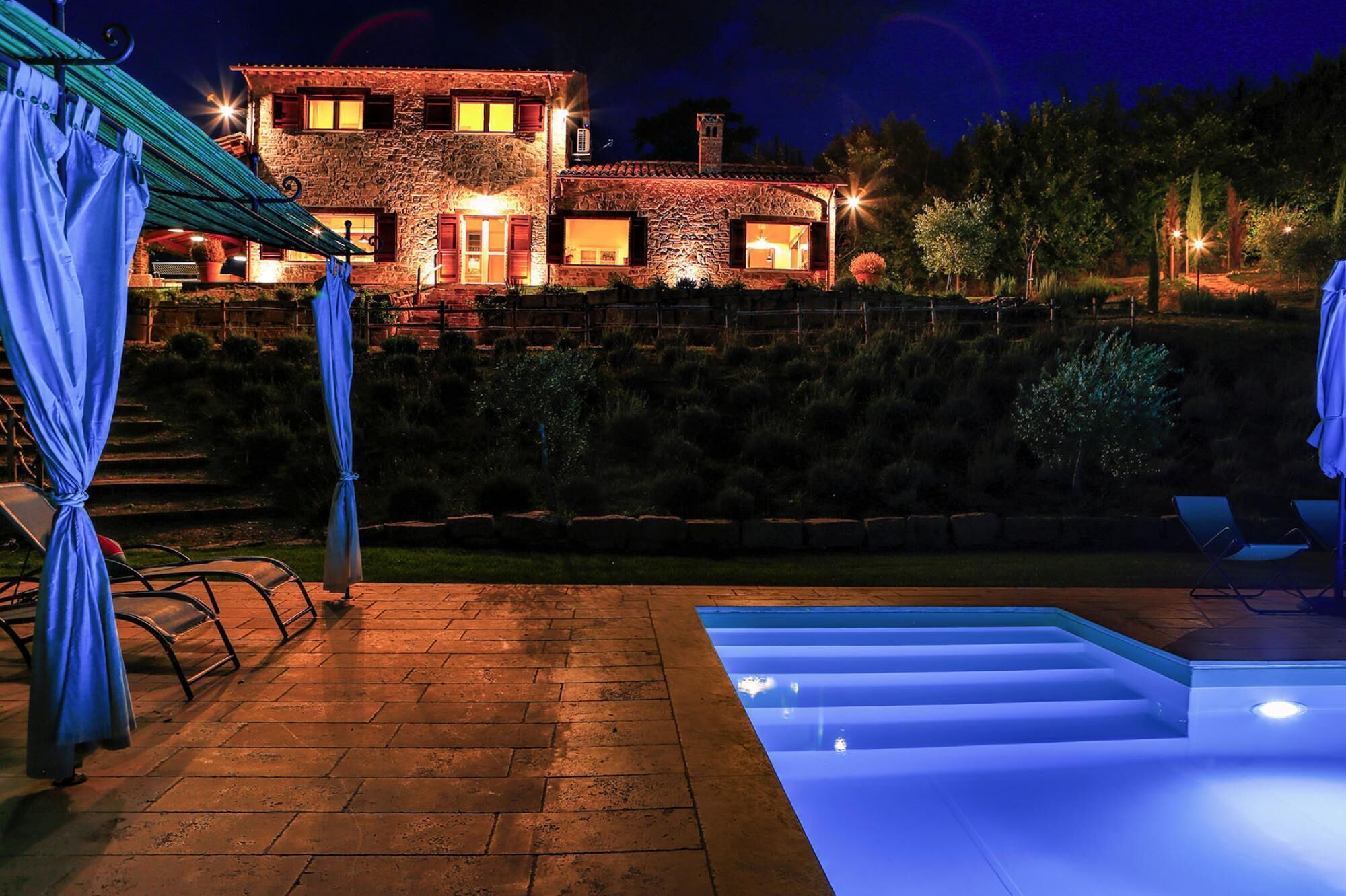 A stone house with a swimming pool at night.