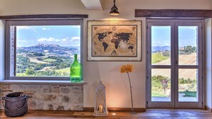 Una habitación con chimenea de piedra, un mapa mundial en la pared, una botella verde, una vela y una flor.