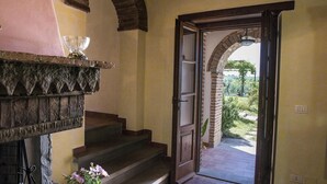 A stone staircase leading to a door with a view of a garden. - Casale Cinque Valli 8 (Cortona)