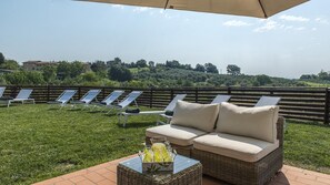 A patio with lounge chairs and a wicker sofa, a table with a drink tray, and a view of a hilly landscape. - Casa Elia 4 2 in Palazzone (San Casciano dei Bagni)