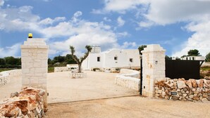 A white building with a stone gate and a tree in the foreground. - White Stone House 6 1 (Ostuni)