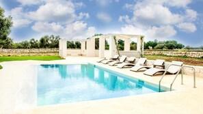 A swimming pool with lounge chairs and a pergola.