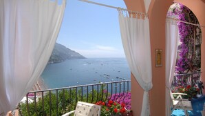 Ein Balkon mit Blick auf das Meer, weißen Vorhängen und einer Statue.