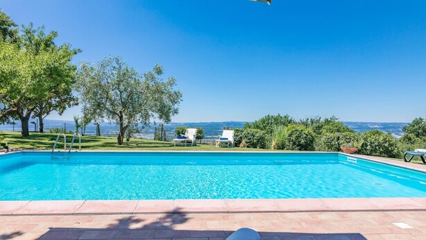Piscina azul e límpida com vista para a paisagem e colinas ao longe.