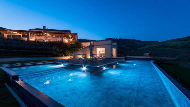 Ett modernt hus med en swimmingpool i skymningen.