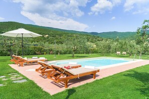 Uma área de piscina com espreguiçadeiras e um pergolado.