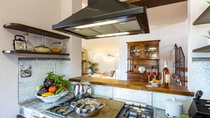 A kitchen with a gas stove, a stainless steel pot, a bowl of vegetables, and a wooden countertop. - Ricciolo 4 in San Gimignano (San Gimignano)