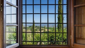 Une fenêtre à carreaux, donnant sur un paysage composé d’arbres et de champs.