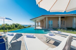 Relax by the pool surrounded by lounge chairs and umbrellas, with a view of the surrounding landscape.