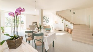 A modern dining area with a table set for four, a staircase, and a view of the outdoors.