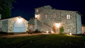 A stone building with a large garage door, a staircase, and a well-lit entrance. - Podere Pisinano 8 2 (Montepulciano)