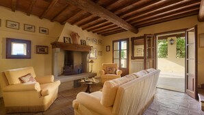 Un salon chaleureux avec une cheminée, des sièges confortables et une vue sur l’extérieur.