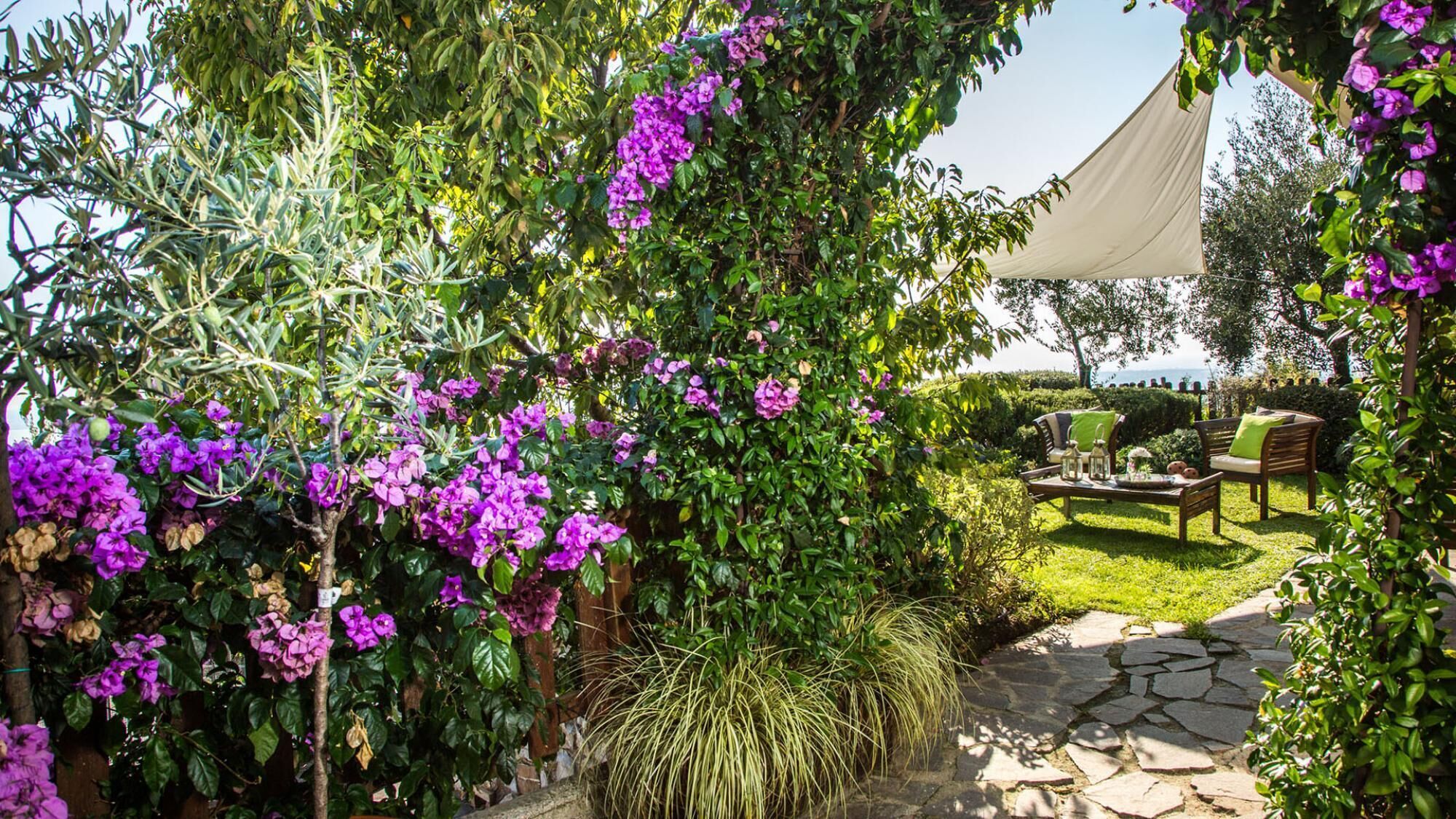 Un jardin avec un chemin de pierres, du mobilier d’extérieur et une tente.