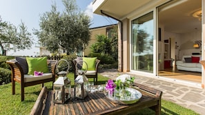 A patio with outdoor furniture, a glass table, and a flower arrangement.