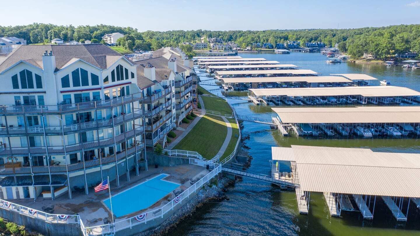 A waterfront hotel with multiple balconies, a swimming pool, and docked boats.