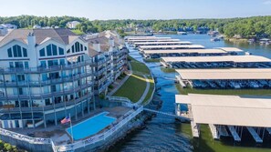 A waterfront hotel with multiple balconies, a swimming pool, and docked boats. - OVERSIZED Master Suite/Lakefront/Jetted tub/Main channel view- Cozy Fireplace! (Osage Beach)