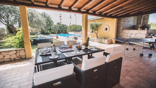 Ein Patio im Freien mit einem für das Frühstück gedeckten Esstisch, umgeben von Korbmöbeln.