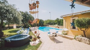 Ein Garten mit Swimmingpool, Liegestühlen und einem dekorativen Hängeelement.