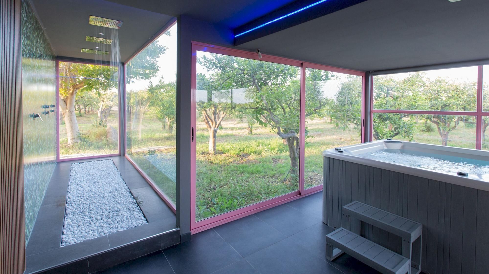 Un espace bien-être avec un jacuzzi, de grandes fenêtres et une vue sur le jardin.