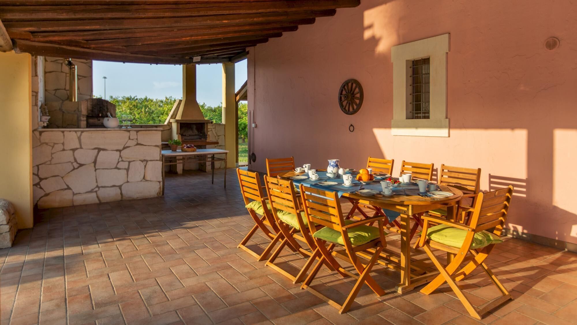 Une terrasse extérieure avec une cheminée en pierre, une table en bois et des chaises.