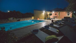 Piscina con sillones de descanso y un patio amoblado al aire libre.