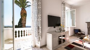 Un salon moderne doté d’un grand téléviseur, d’une cheminée, d’un balcon agrémenté d’un palmier et offrant une vue sur la mer.