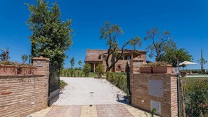 A brick building with a gravel driveway leading to a gated entrance.