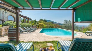 A pool area with lounge chairs, a table with drinks, and a view of the mountains. - Il Casale Del Nonno 8 2 (Guardea)