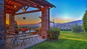 Relax on the patio surrounded by lush greenery and a picturesque view of the distant town.