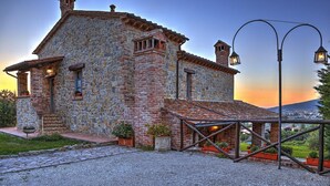 A stone building with a tiled roof, a small porch with potted plants, and a street lamp. - San Rocco 4 in Montecchio (Montecchio)