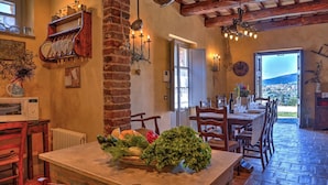 A rustic kitchen with a brick wall, wooden furniture, and a view of a town through an open door. - San Rocco 4 in Montecchio (Montecchio)