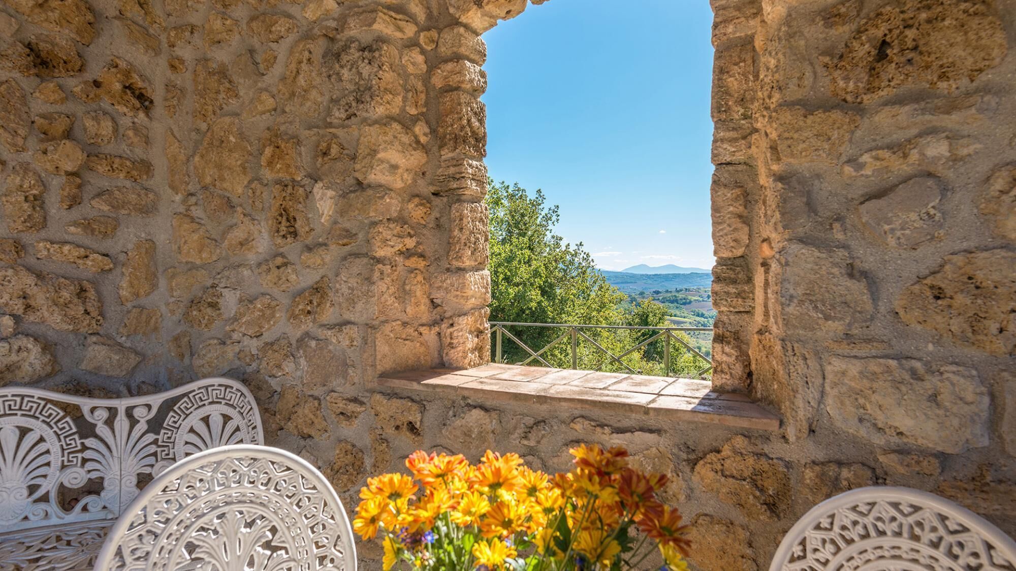 A stone wall with a window overlooking a green landscape.