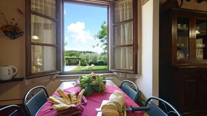 Ein Essbereich mit einem Tisch für vier Personen, einem Fenster mit Blick auf einen Garten und einer Vitrine.