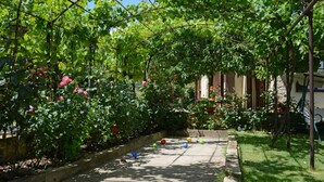 Ein Garten mit einer Pergola, üppigem Grün und einem Pfad.