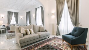 A spacious living room with a grey sofa, a blue armchair, and a patterned rug. - Villa La Perla Bianca 10 (Empoli)