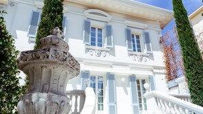 A classical building with white walls and blue shutters, featuring a central decorative column and a staircase leading to the entrance. - Villa La Perla Bianca 10 (Empoli)