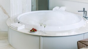 A modern bathroom with a large oval bathtub, a white marble countertop, and a small bowl of strawberries. - Villa La Perla Bianca 10 (Empoli)