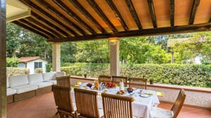 An outdoor patio with a dining table set for four, surrounded by wooden chairs.