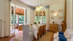 A dining area with a table set for four, a wicker chair, a cabinet, and a blue sofa.