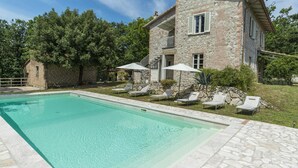 A stone building with a swimming pool, surrounded by trees and equipped with lounge chairs and umbrellas. - Villa La Corte 6 in Montecastrilli (Montecastrilli)