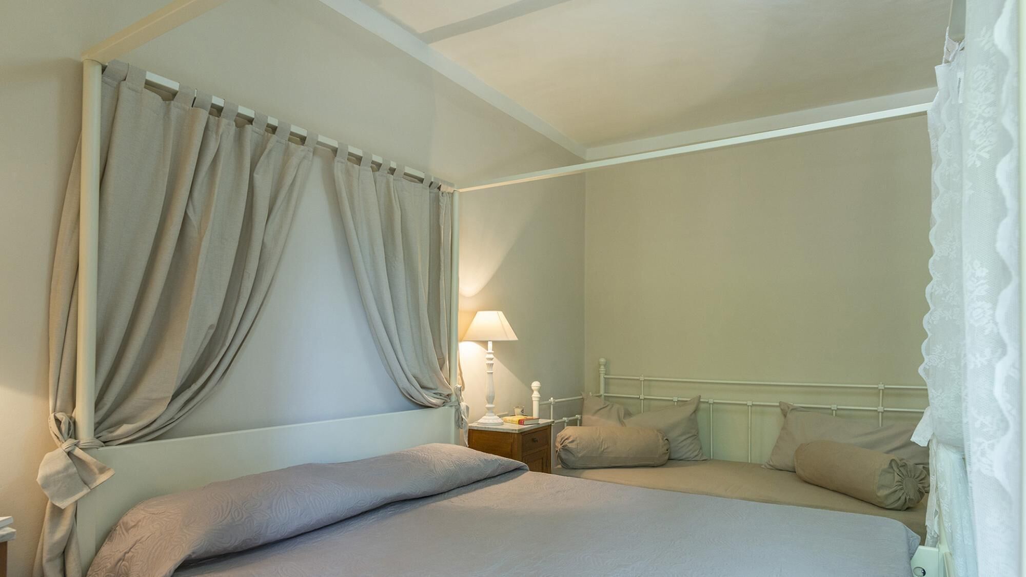 A bedroom with a bed, nightstand, lamp, and curtains.