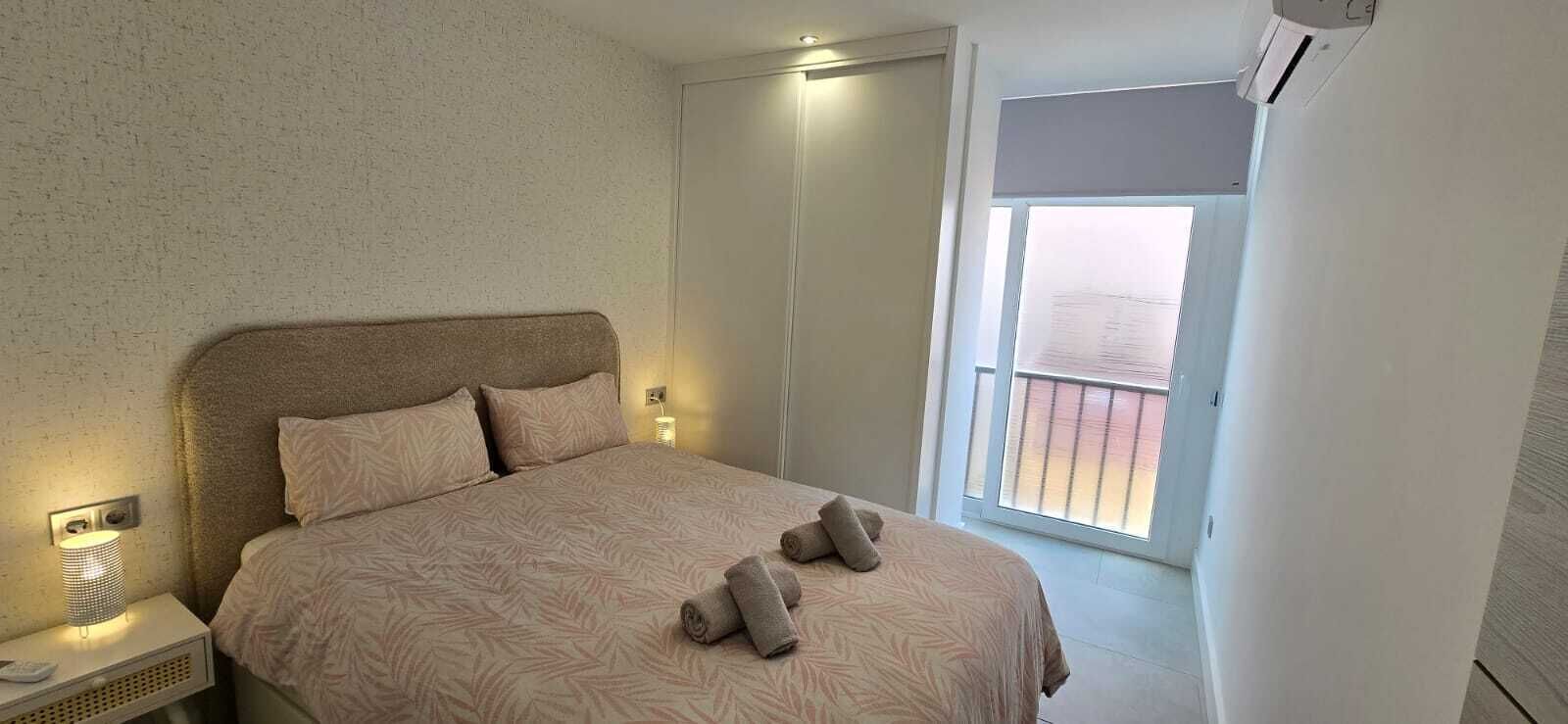 Een slaapkamer met een bed, twee bedlampen, een raam met uitzicht en een airconditioning.