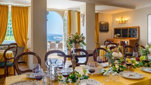 A dining room with a table set for a meal, chairs, and a view through an open window. - Tenuta Di Pratello 24 (Peccioli)