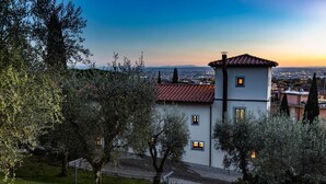 A two-story building with a red-tiled roof, multiple windows, and a view of a cityscape at sunset. - Torre Angelina 10 2 (Montecatini Terme)