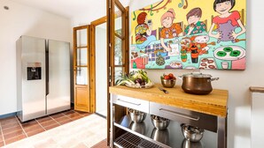 A kitchen with a stainless steel refrigerator, a wooden door, a countertop with a pot, bowls, and fresh vegetables. - Torre Angelina 10 2 (Montecatini Terme)