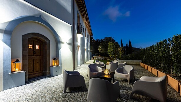 An outdoor seating area with modern chairs and tables, a wooden door, and lanterns. - Torre Angelina 10 2 (Montecatini Terme)