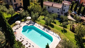 A swimming pool with a deck, surrounded by greenery and a building in the background. - Torre Angelina 10 2 (Montecatini Terme)